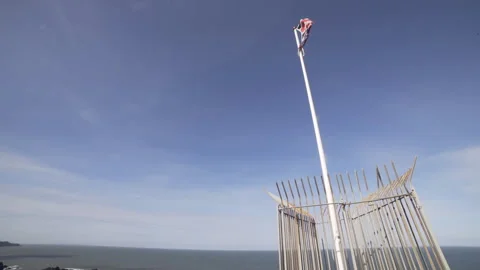 Pan from British flag in wind to coastal town and beach Stock Footage 136907716