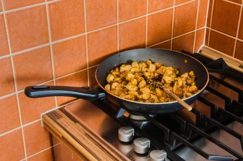 Pan with chines modified beef on the cooker in orange kitchen. Stock Photos