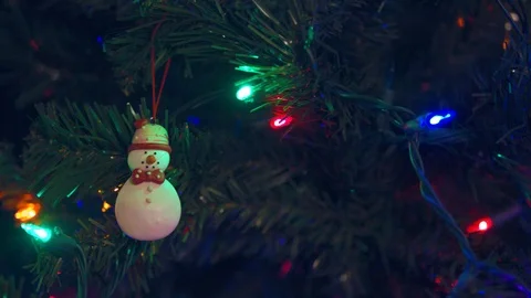 Pan onto a Christmas Tree with Flickering Lights and a Snowman Ornament Stock Footage 98965741