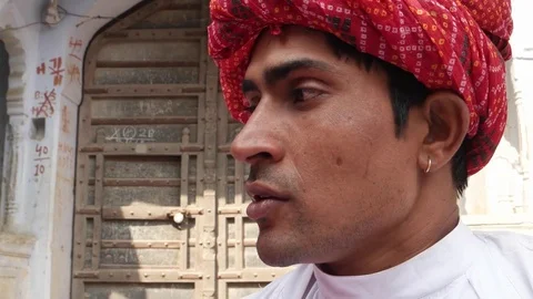 Pan close up from a handsome man with red turban to a pretty lady in pink sari t Stock Footage 69930773