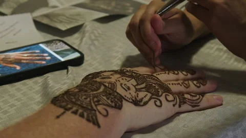 Pan to closeup of henna artwork being applied to back of man's hand Stock Footage 335125912