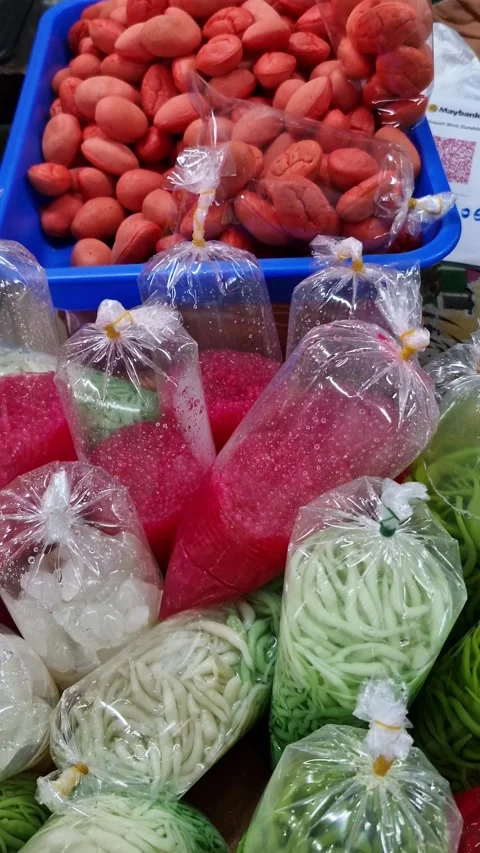 Pan up of colorful local Malay drinks 'cendol' and 'sago' in a plastic Stock Footage 330108394