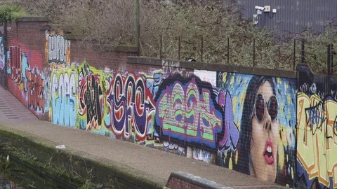 Pan of Colourful graffiti reflected in the rippling waters of Birmingham canal Video stock 72439061