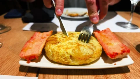Pan con tomate and tortilla served on a plate. In a cozy restaurant setting, a Stock Footage 329996989
