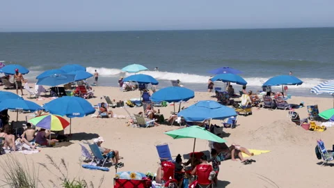 Pan-Crowd flock to Bethany Beach Atlantic seashore on warm windy day Stock Footage 202340526