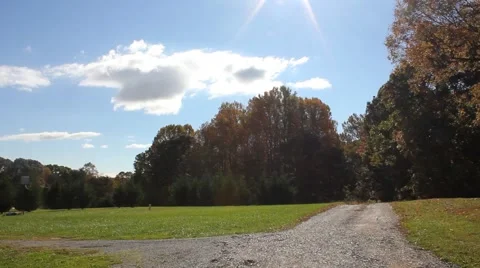 Pan up from a dirt road to a bright sun overhead Stock Footage 44447214