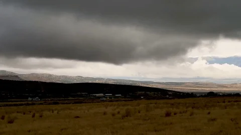 PAN-Distant sun lit valley under dark foreboding rain clouds and foreground-4K Stock Footage 80091924