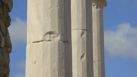 Pan down to 2,000 year old columns on the island of Delos, Greece Stock Footage 108568169