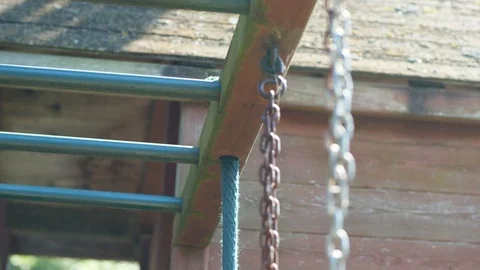 Pan down along weathered chain monkey bar and rope of child playset in Garden Video stock 95032529