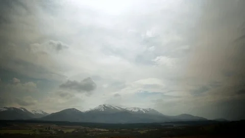 Pan down from Clouds and sun to reveal snow filled mountains in Scotland 動画素材 72671961