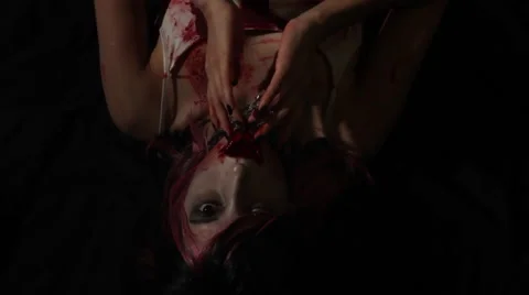 Pan Down on Cute Vampire Girl Laying Down Licking Blood from Her Fingers CU Stock-Footage 41508258