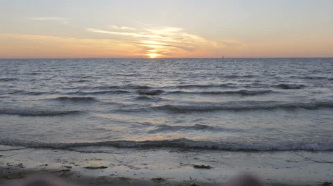 Pan down of a hand made heard encompassing the sun down at the beach Stock Footage 51463832
