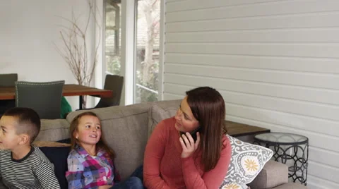 Pan down of mother on the phone with two children Video stock 67356646