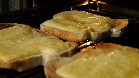 Pan down over cooked cheese on toast under a grill Stock-Footage 98661047