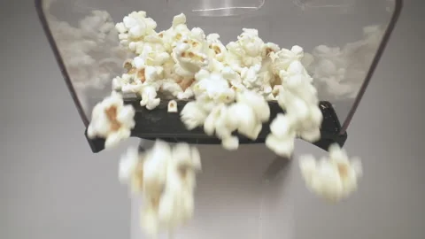 Pan down from a popcorn machine as popcorn piles up high. Stock Footage 130835145
