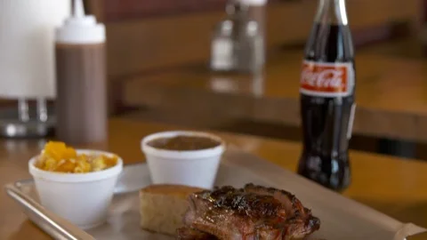 Pan down of ribs with coke and sides  動画素材 112575799