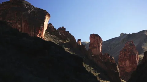 PAN DOWN ROCK FORMATIONS ON HILLSIDE MOUNTAIN RIDGE IN BACKGROUND LATE AFTERNOON Stock Footage 51775727