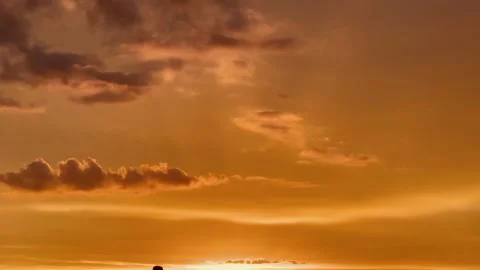 Pan down of the sunset on the beach with people watching Stock Footage