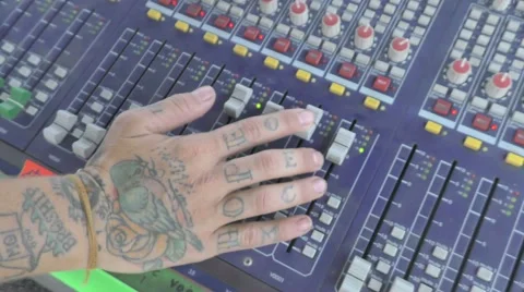 Pan down to tattooed hand on audio board Stock Footage 57402833