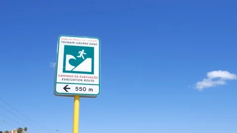 Pan down of a tsunami evaculation route sign next to a seaside promenade with Stock Footage 109286846