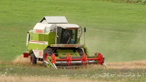 Pan: farmer doing farm work riding combine harvester in rural Germany Stock Footage 246831100