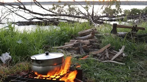 Pan is on fire on the background of the river, wood and an ax. Stock Footage 53885483