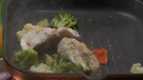 The pan-flip of veggies and fish above the grill Stock Footage 139698260