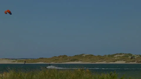 Pan follow kite surfer speeding across &amp; leaping from the waters of Safety Bay Stock Footage 229457791