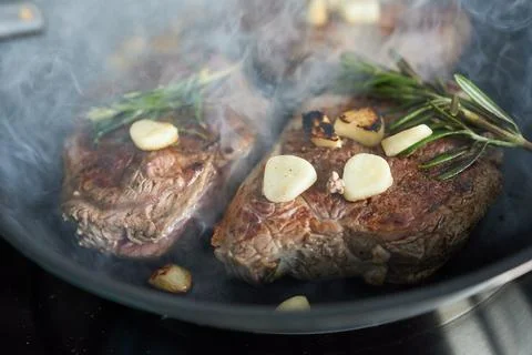 Pan-fried beef steaks with garlic and rosemary. Stock Photos