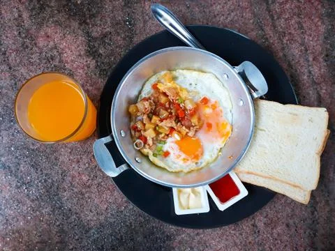 Pan-fried egg with toppings ,bread and orange juice. Stock Photos