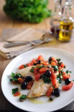 Pan fried fillets of John Dory with baby plum tomatoes and black olives and Stock Photos