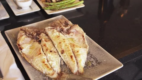Pan-fried white fish on a rectangular plate. Restaurant dish - hake in oil. 스톡 동영상 258661303