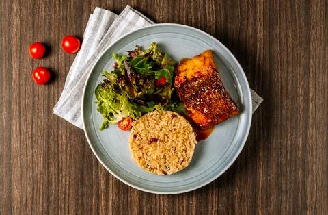 Pan Fried Wild Cod Fish with fried rice isolated on wooden background top vie Stock Photos