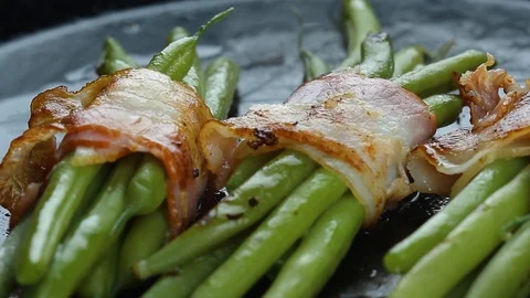 Pan frying green string beans wrapped with bacon Stock Footage 124831657
