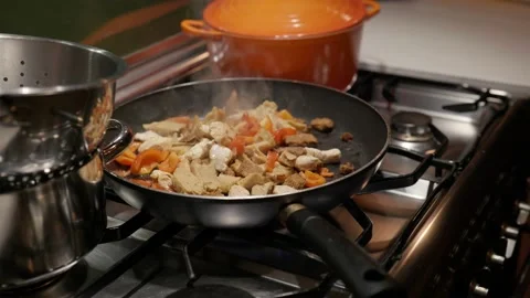 Pan on gas stove in kitchen baking mix of poultry and peppers Видео 220768022