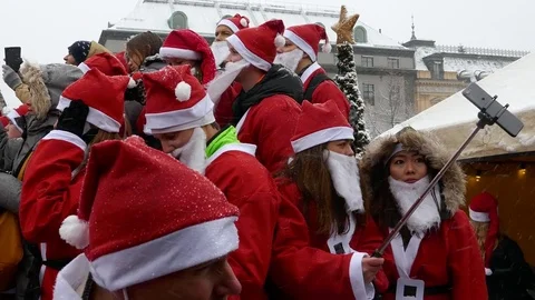 Pan on gathering of crowd of Santa Clauses taking selfie photo with mobile Stock Footage 70642642