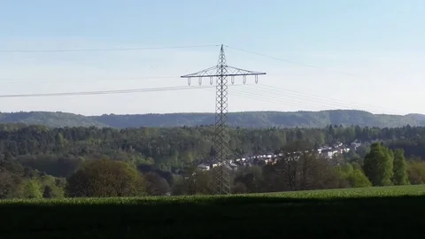 Pan: Green fields, agriculture, forest, power pylons, power lines, rural suburb Stock Footage 76772347