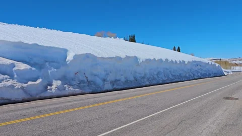 Pan Huge snow drift lines a high mountain road Stock Footage 240649433