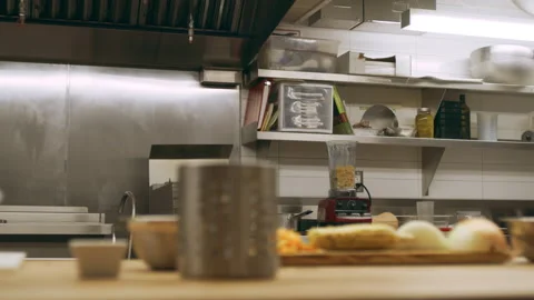 Pan of kitchen tools including bowls and cutting board with vegetables on counte Stock Footage 199458871