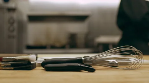 Pan of kitchen tools including whisk, brushes, torch, bowls and cutting board wi Stock Footage 199457430