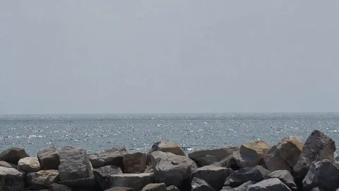 PAN L-R OF ROCK BREAKWATER WITH KAYAKERS IN THE WATER Stock Footage 106138853