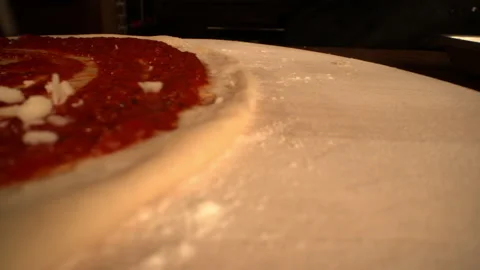 PAN LEFT CLOSE UP OF CHEESE FALLING ONTO HAND MADE PIZZA Video stock 130410405