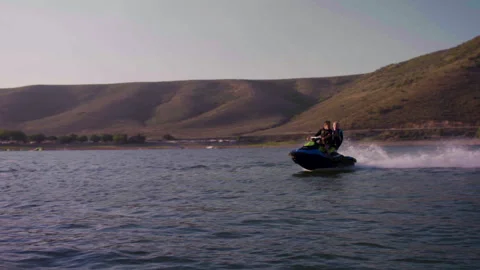 Pan left Full shot of two guys riding one wave runner going left with moutai Stock Footage 167803405