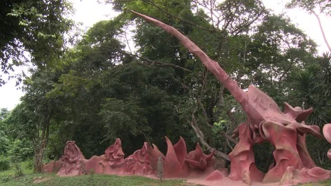 Pan left over pink petal-like sculptures, a motorcycle passes by. Stock Footage 86760833