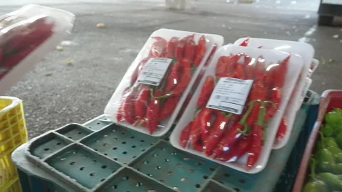 Pan Left Over a Red Chili Pepper Display as a Hand Takes a Tray Stock Footage 340557800