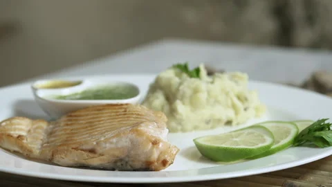 Pan left on a plate of roasted salmon with potato, lemon and sauce Stock Footage 135278767