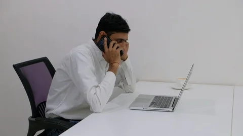 Pan left to right as colleague talks on smart phone and passes it to his coworke Stock Footage 100025944