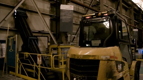 Pan Left to Right as Forklift moves away from camera in Modern Factory Stock Footage 89944497