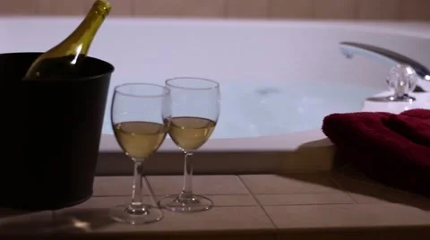 Pan from left to right past bubbling jacuzzi wine and towels Stock Footage 58669462