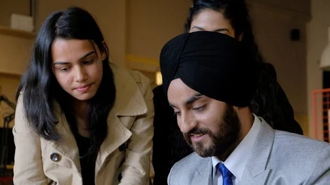 Pan left to right as a Sikh boss with turban looks disdainfully as his senior co Stock Footage 101890581